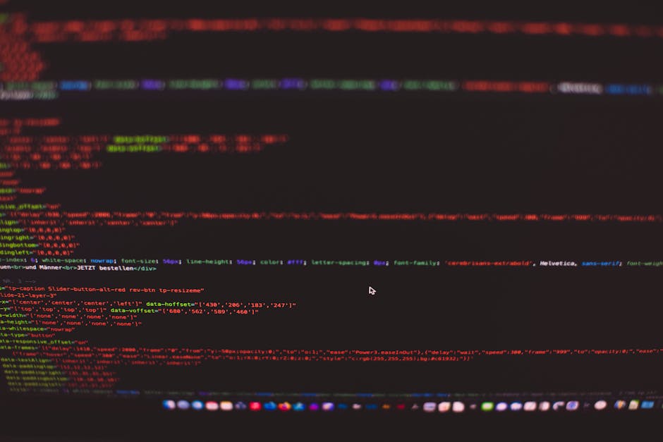 A close-up photograph of a computer screen displaying colorful lines of HTML and CSS code against a dark background, with the code arranged in horizontal rows. The screen shows various tags and attrib